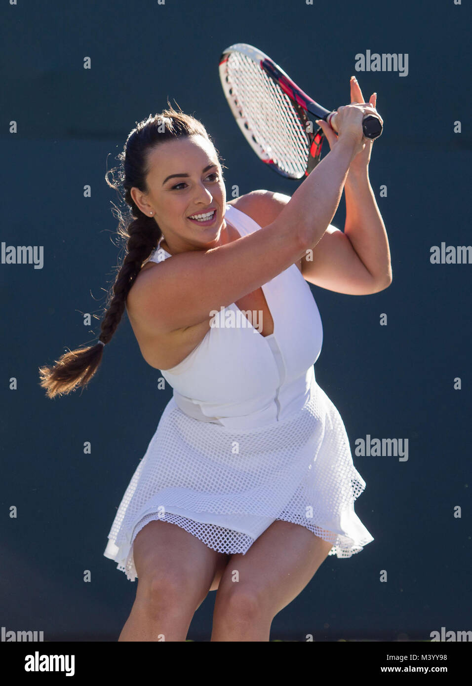A young woman tennis player smiles after hitting a backhand on a tennis court in Beverly Hills, California. Photo by Francis Specker Stock Photo