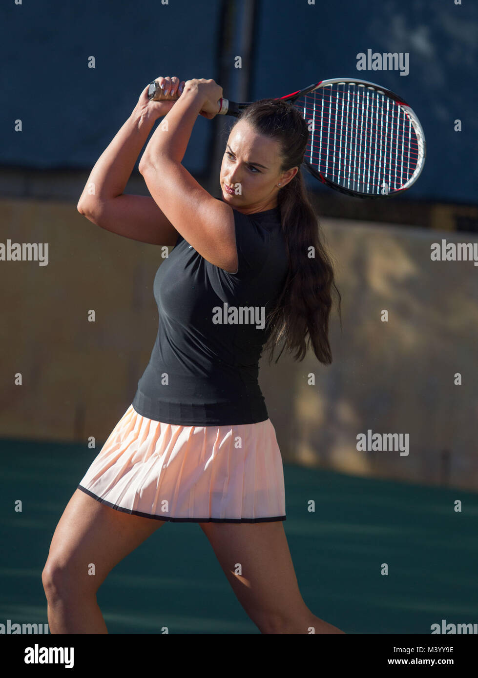 A young woman tennis player hits a two handed backhand on a tennis court in Beverly Hills, California. Photo by Francis Specker Stock Photo