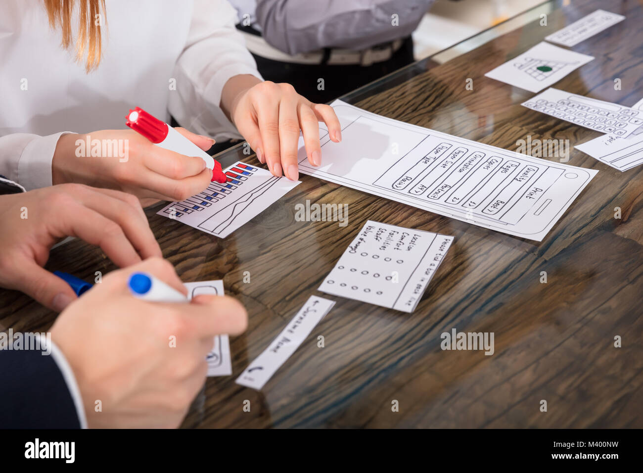 Designers Developing Mobile Application On Paper Over Desk Stock Photo
