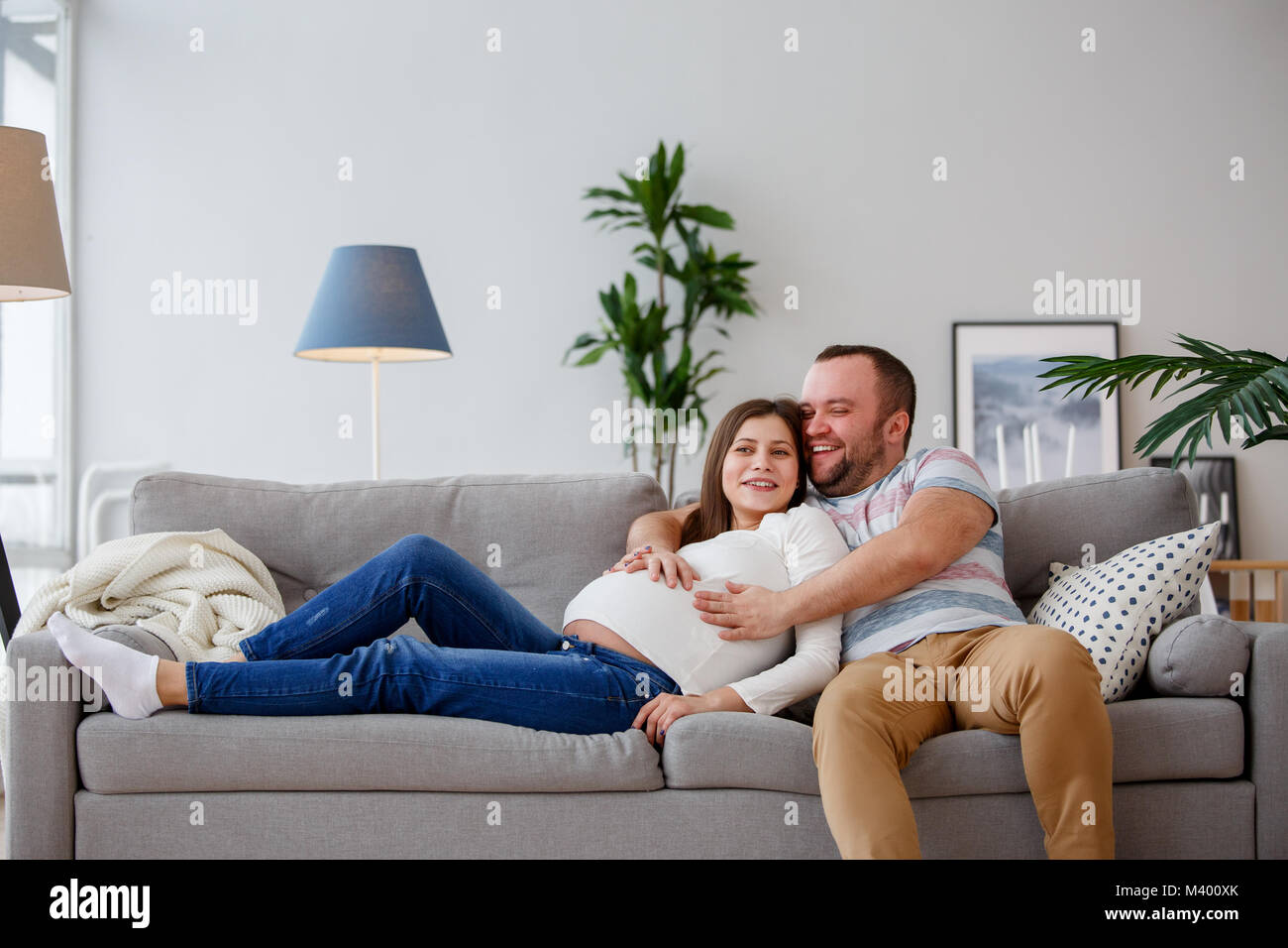 Image of happy future parents sitting on gray sofa Stock Photo
