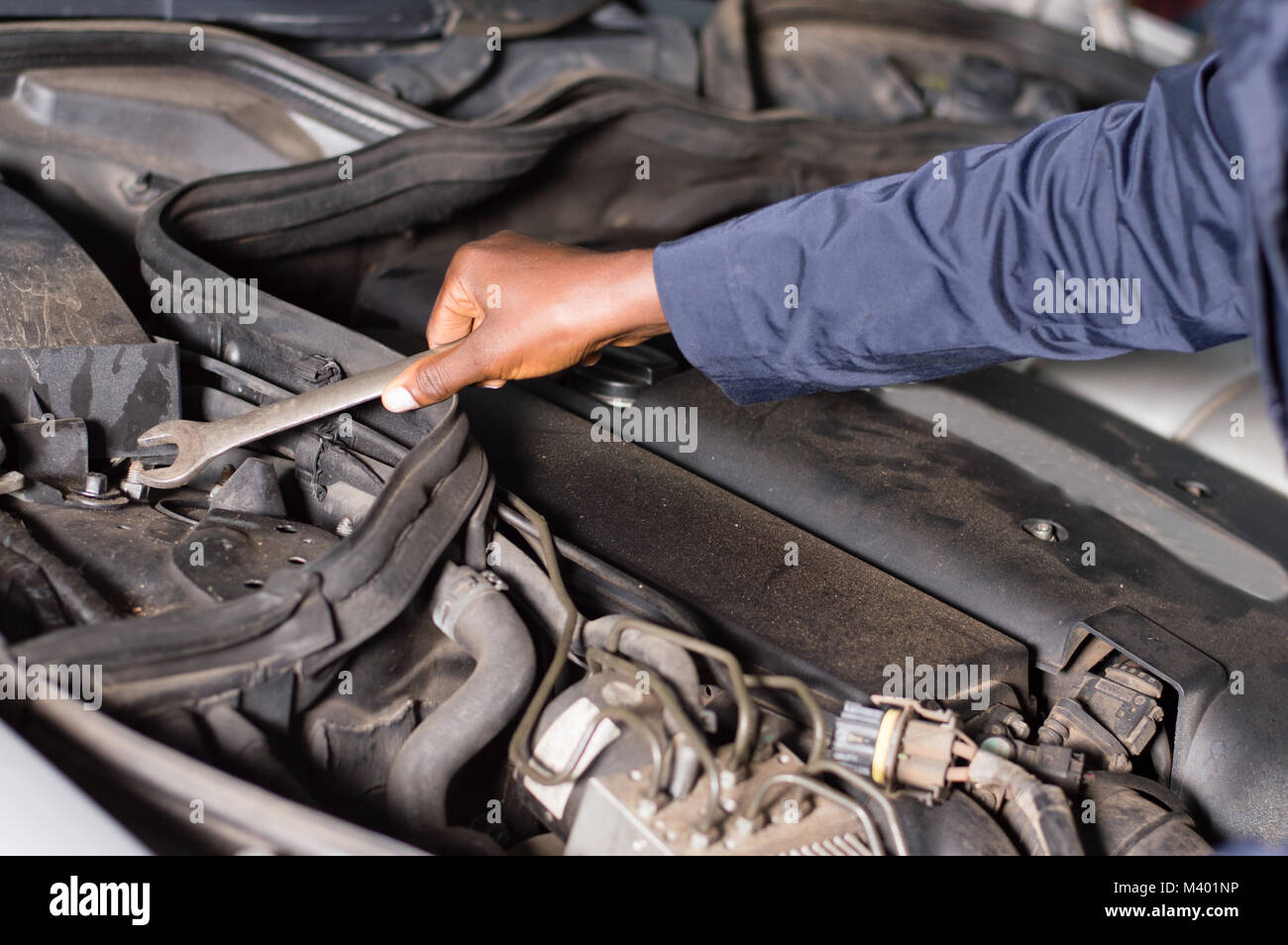 Close-up of a hand holding a key on the engine of a broken car. Stock Photo