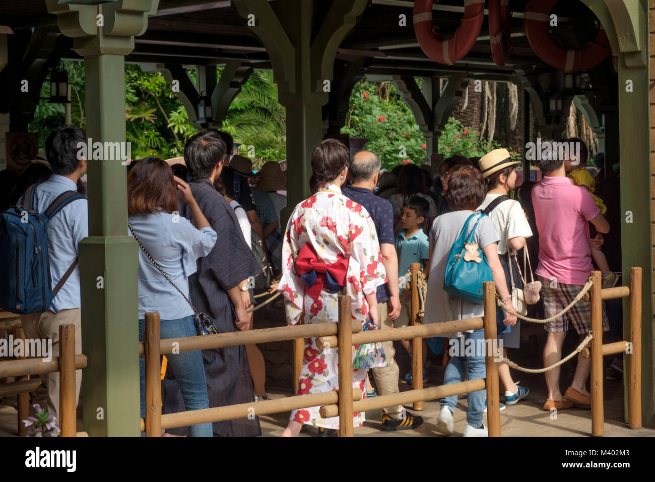 Japanese people queuing to see Disneyland Tokyo attraction. One lady in kimono. Stock Photo
