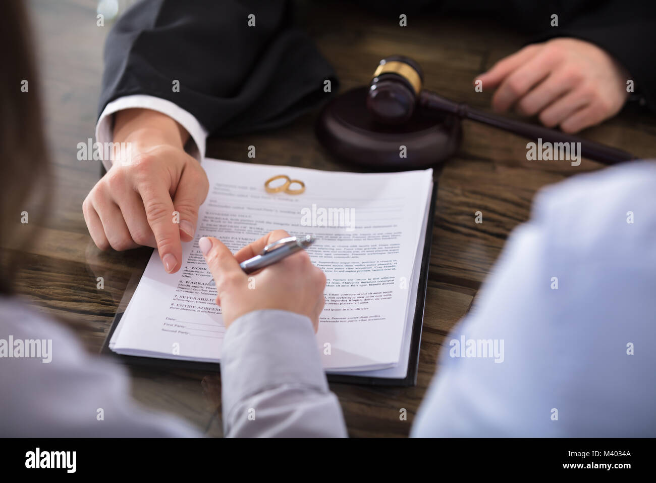 Close-up Of A Female Signing Contract On Desk In Courtroom Stock Photo