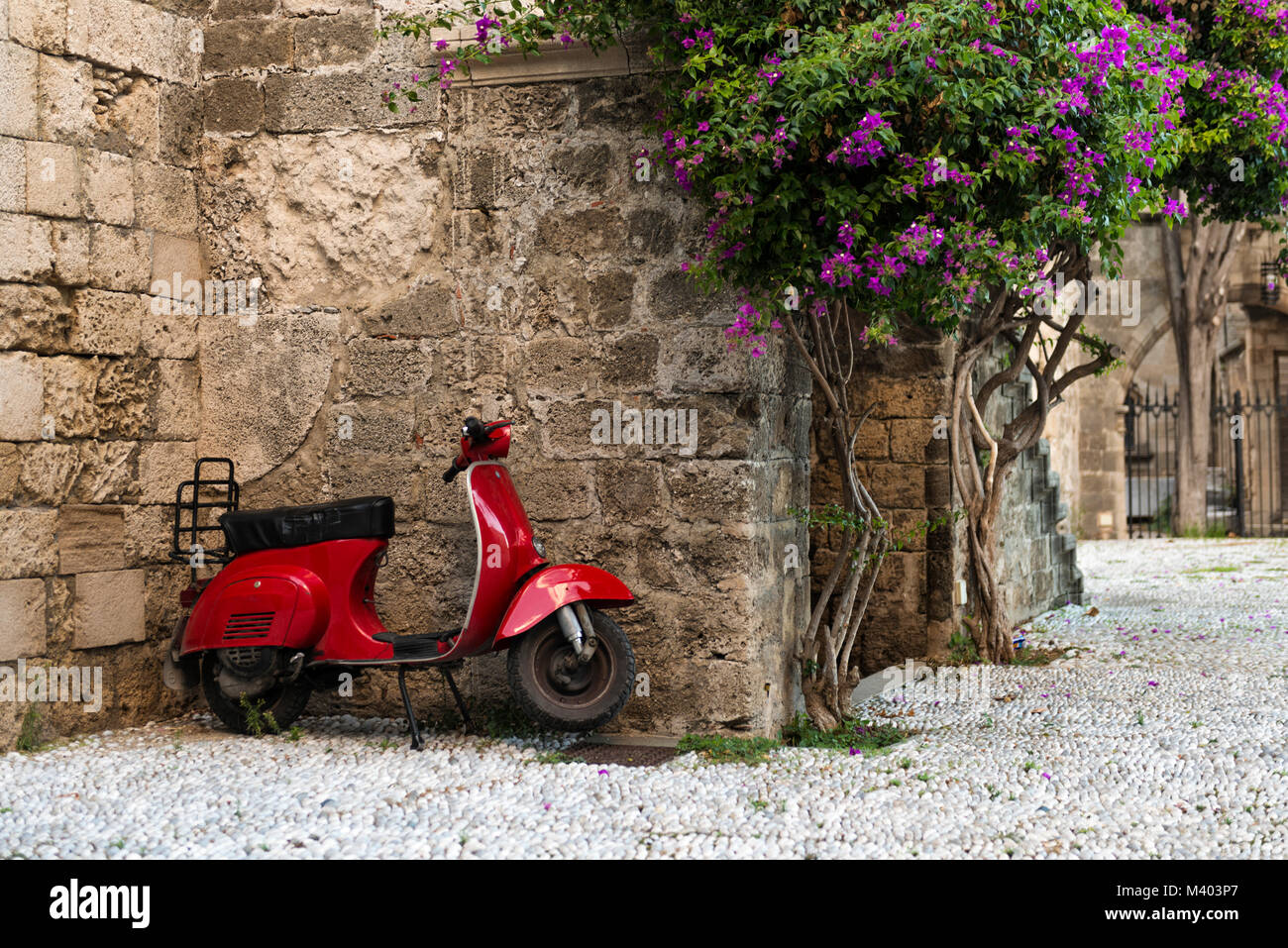 An old red Vespa motor scooter parked beside some derelict buildings in Rhodes Town,  on the Greek island of Rhodes, Greece Stock Photo