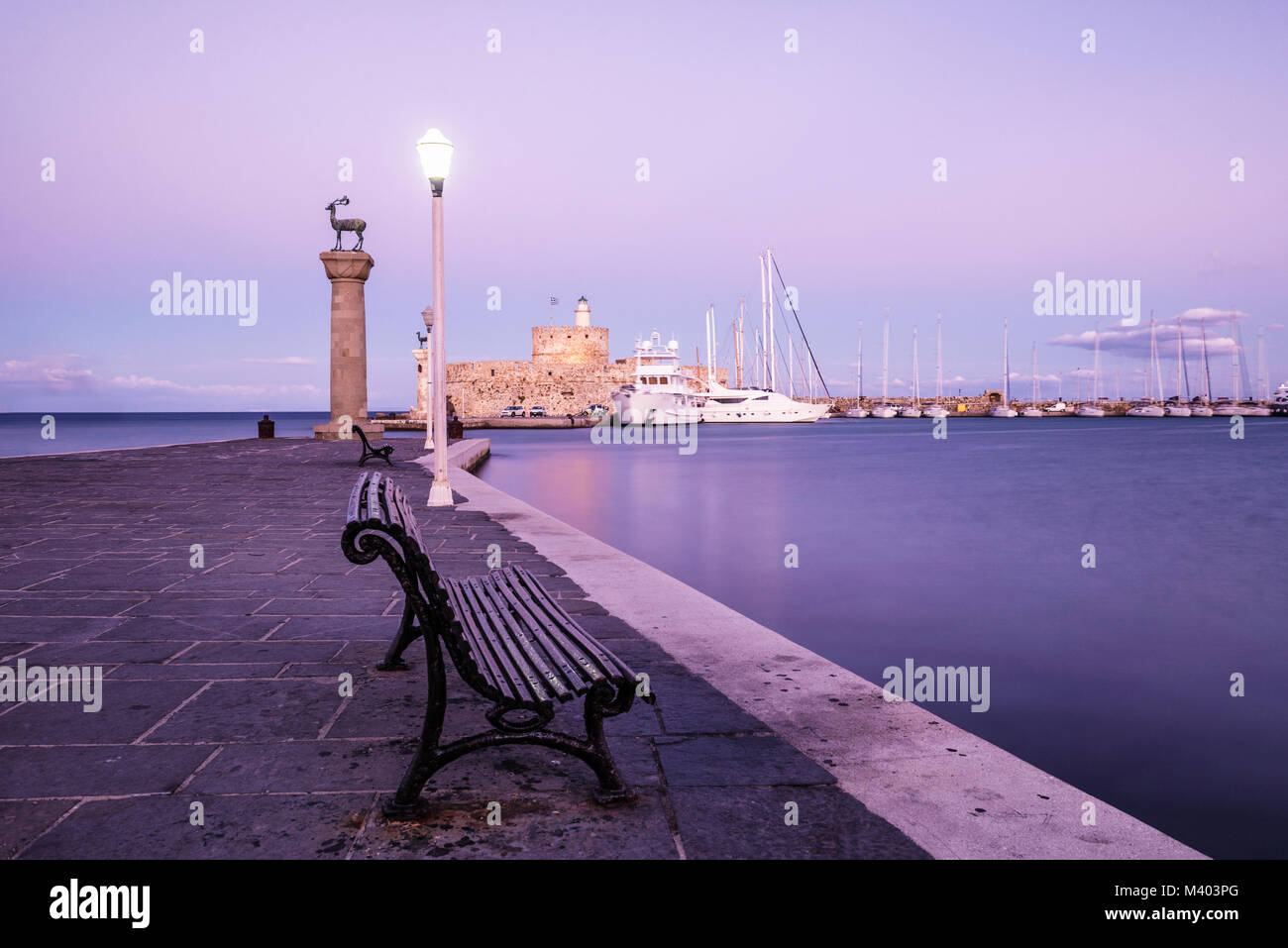 Mandraki harbour and fortress Agios Nicolaos in Rhodes town after sunrise, Rhodes Island, Greece, UNESCO Stock Photo