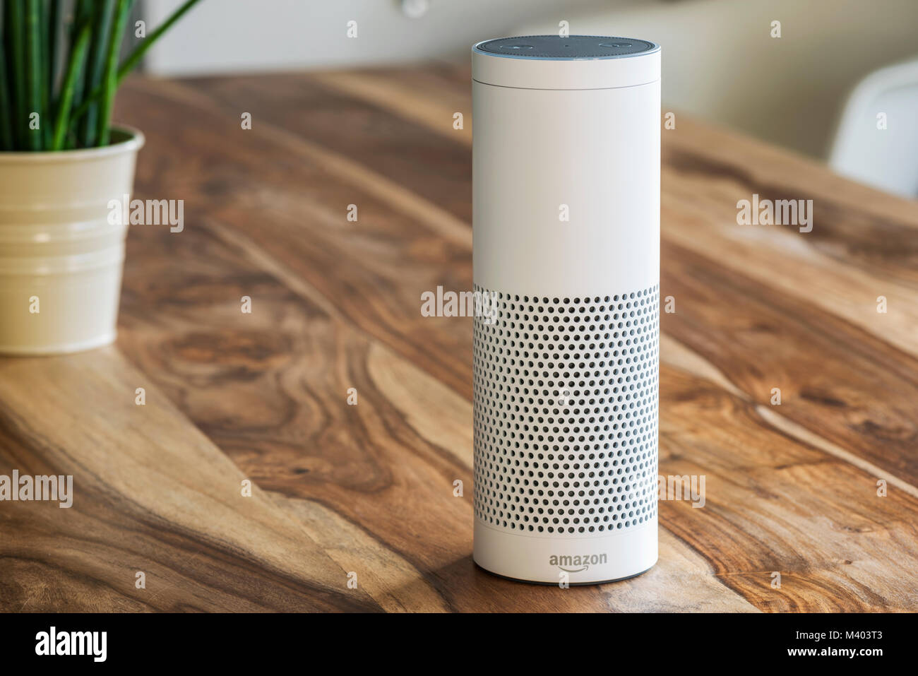 MUENSTER - JANUARY 27, 2018: White Amazon Echo Plus, Alexa Voice Service activated recognition system photographed on wooden table in living room Stock Photo