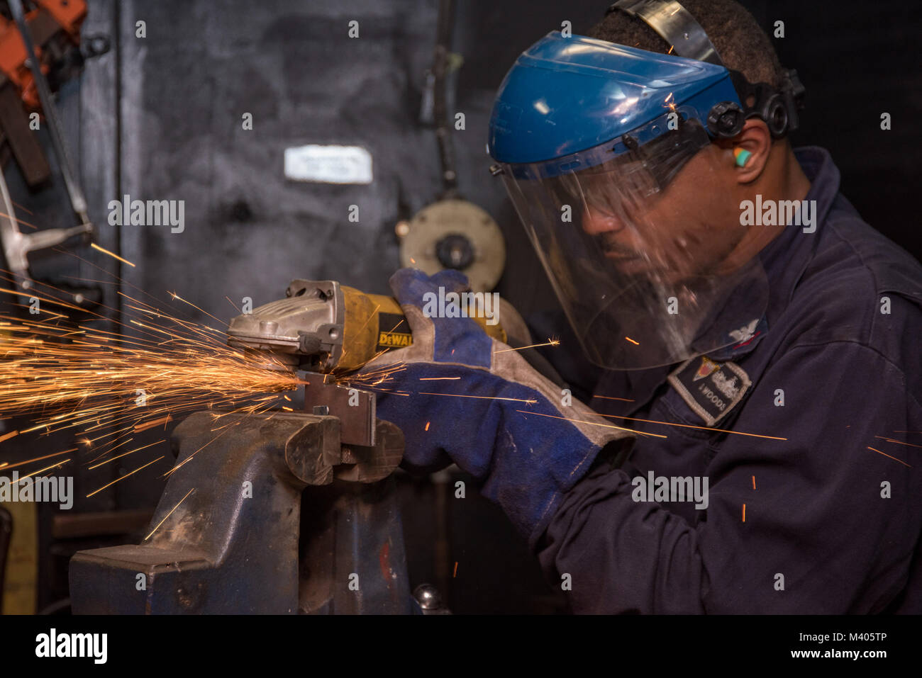 180206-N-CG677-0026  PACIFIC OCEAN (Feb. 6, 2018) Hull Technician 3rd Class Devonta Woods grinds a piece of metal in the machine shop of the Nimitz-class aircraft carrier USS Carl Vinson (CVN 70). Carl Vinson Strike Group is currently operating in the Pacific as part of a regularly scheduled deployment. (U.S. Navy photo by Mass Communication Specialist 3rd Class Jake Cannady/Released) Stock Photo