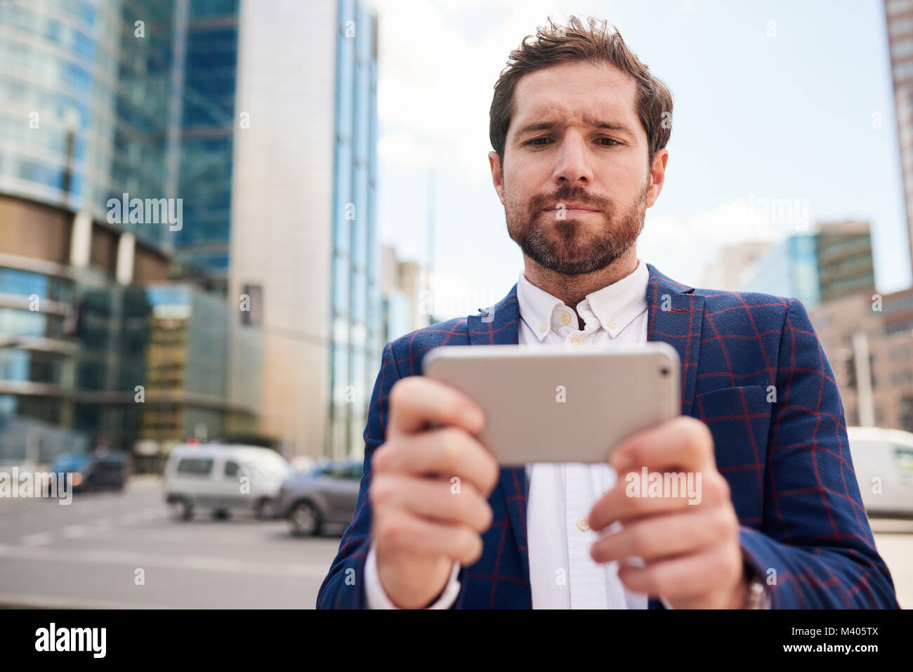 Young businessman standing on a city street using his smartphone Stock ...