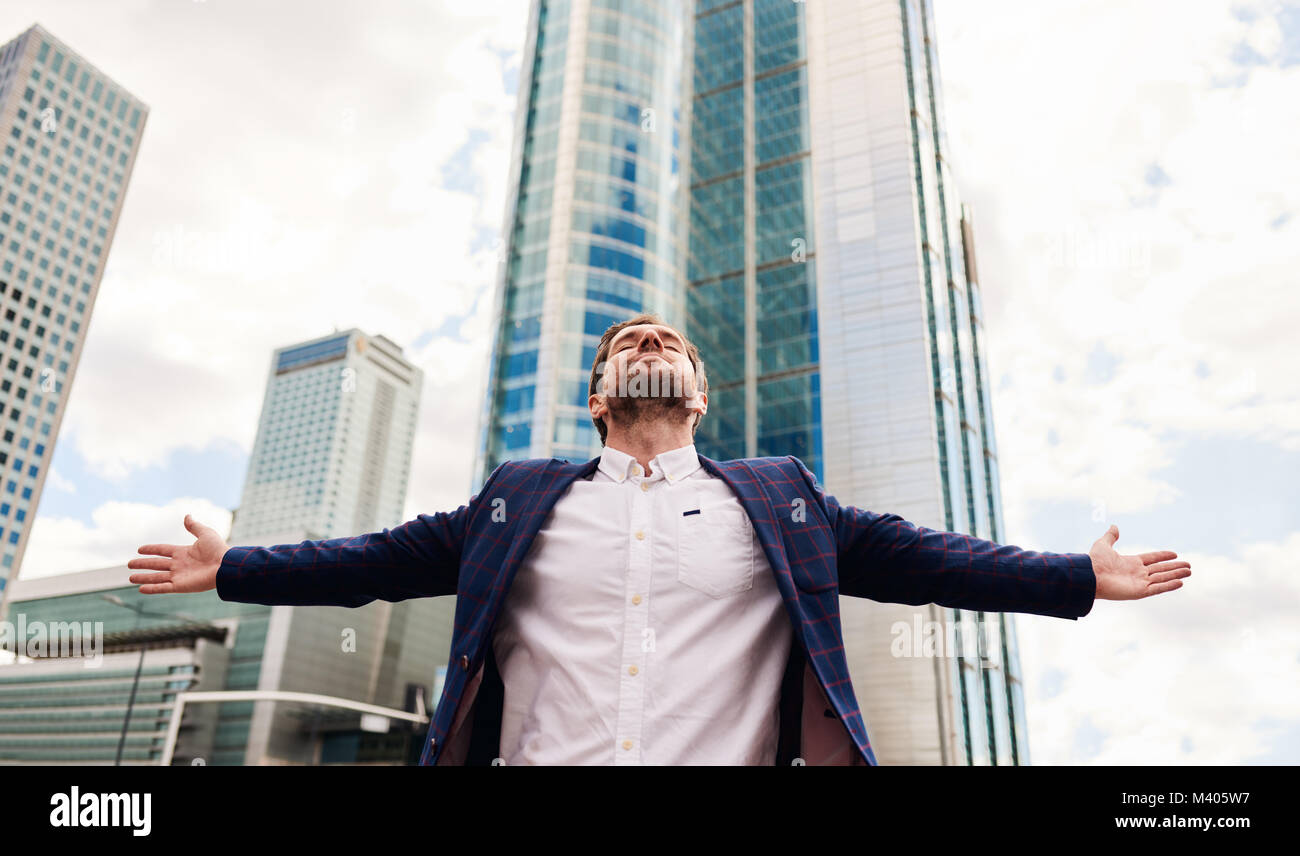 Businessman with arms raised skyward standing in the city Stock Photo