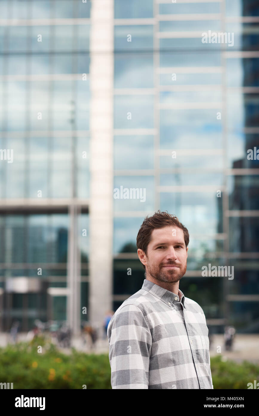 Smiling young man standing alone on a city street Stock Photo - Alamy