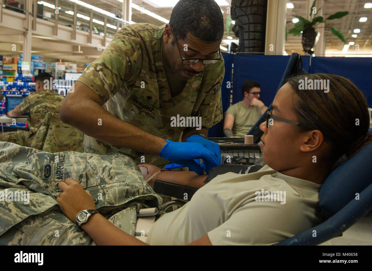 U.S. Army Spc. Benjamin Wright, Tripler Army Medical Center phlebotomist, draws blood from U.S. Air Force Airman 1st Class Noelle Hong, 324th Intelligence Squadron intelligence analyst, during a blood drive at the Base Exchange, at Joint Base Pearl Harbor-Hickam, Feb. 6, 2018. The Tripler Army Medical Center Blood Donor Center holds multiple donation events a week, along with their clinic hours, to collect blood that will be used to treat military members, families, and veterans at home and abroad. (U.S. Air Force photo by Tech. Sgt. Heather Redman) Stock Photo