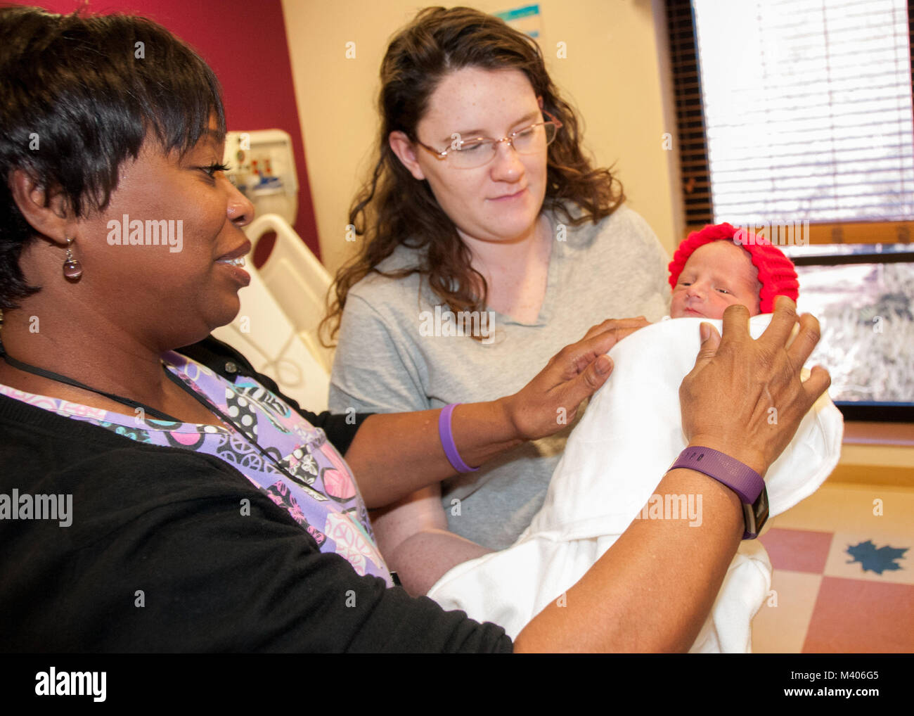Theresa Perry, Licensed Vocational Nurse, Postpartum Unit, William Beaumont Army Medical Center, helps Kayla Simons, first-time mom and Fort Bliss military spouse, adjust newborn Hunter Simons’ blanket as he dons a little red hat, part of a nationwide initiative aimed at empowering moms to live heart-healthy lives and encouraging children to do the same in honor of Congenital Heart Defect Awareness Week (Feb. 7-14), at WBAMC, Feb. 7. Stock Photo