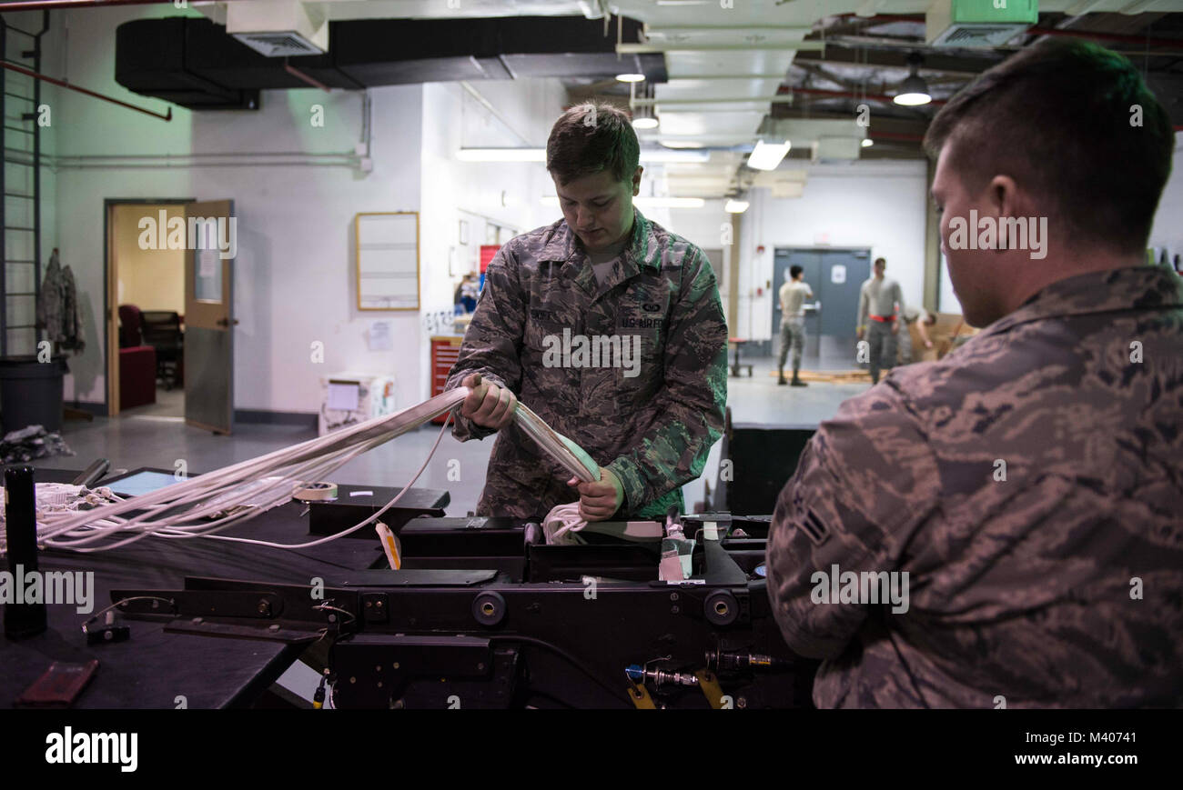 Airmen from aircrew flight equipment and egress work together to pack a parachute into an F-15 Eagle ejection seat, Feb. 7, 2018, at Kadena Air Base, Japan. The shops have different specialties but often times work closely together. (U.S. Air Force photo by Senior Airman Jessica H. Smith) Stock Photo