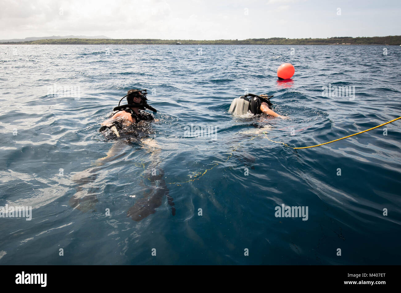 Explosive Ordnance Disposal Technician 3rd Class Jake Ballard and Explosive Ordnance Disposal Technician 3rd Class James Webb, both assigned to Explosive Ordnance Disposal Mobile Unit 5 (EODMU-5), swim to a buoy before diving during underwater mine countermeasures training in Apra Harbor, Guam, Feb. 7, 2018.EODMU5 conducts counter IED operations, renders safe explosive hazards and disarms underwater explosives. EODMU-5 is assigned to Commander, Task Force 75, the primary expeditionary task force responsible for the planning and execution of coastal riverine operations, explosive ordnance dispo Stock Photo
