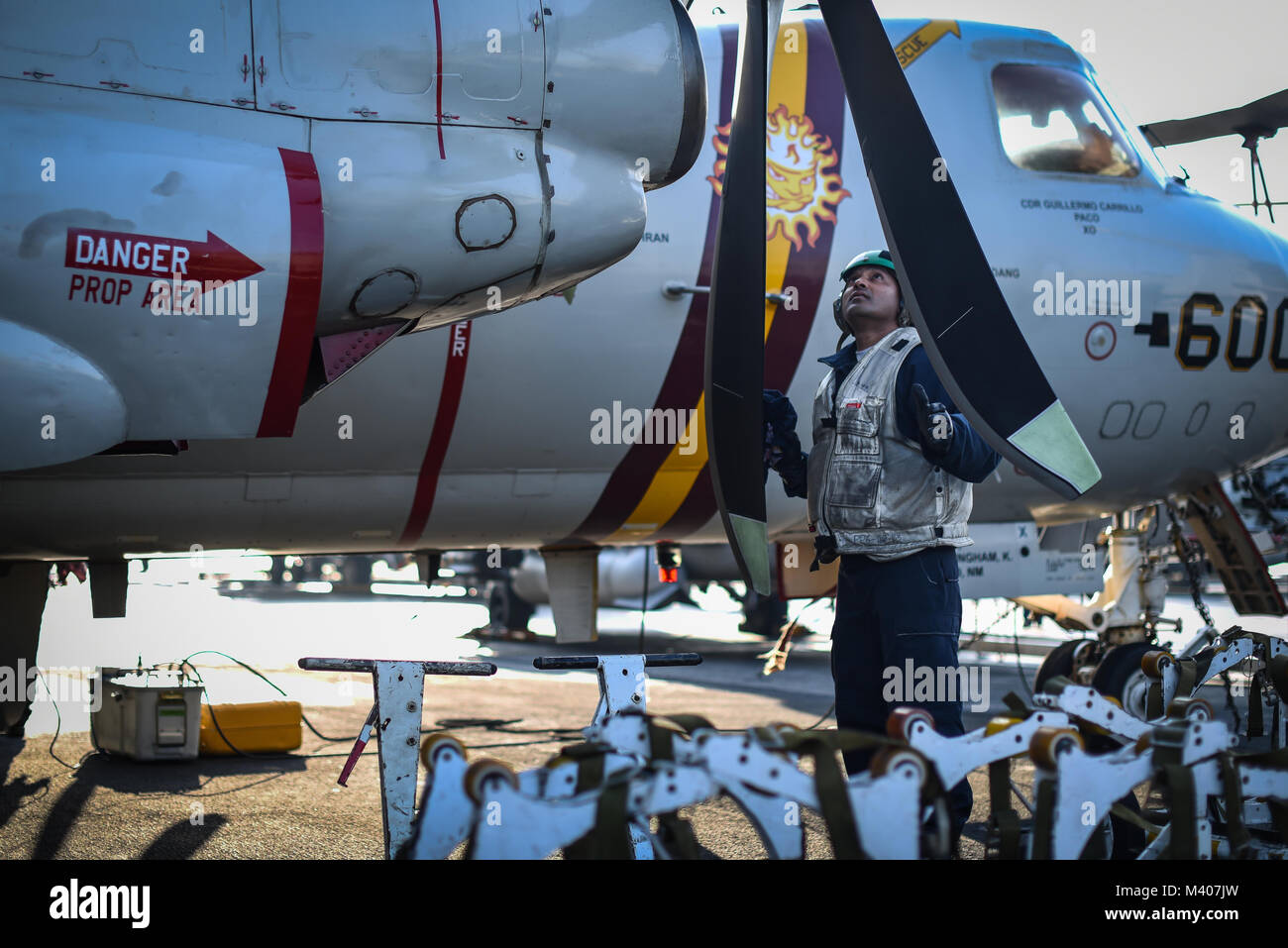 180208-N-VN584-1317 ARABIAN GULF (Feb. 8, 2018) Aviation Machinist’s Mate 2nd Class Bhakta Siwa, assigned to the Sunkings of Carrier Airborne Early Warning Squadron (VAW) 116, checks the propellers of an E-2C Hawkeye on the flight deck of the aircraft carrier USS Theodore Roosevelt (CVN 71). Theodore Roosevelt and its carrier strike group are deployed to the U.S. 5th Fleet area of operations in support of maritime security operations to reassure allies and partners and preserve the freedom of navigation and the free flow of commerce in the region. (U.S. Navy photo by Mass Communication Special Stock Photo