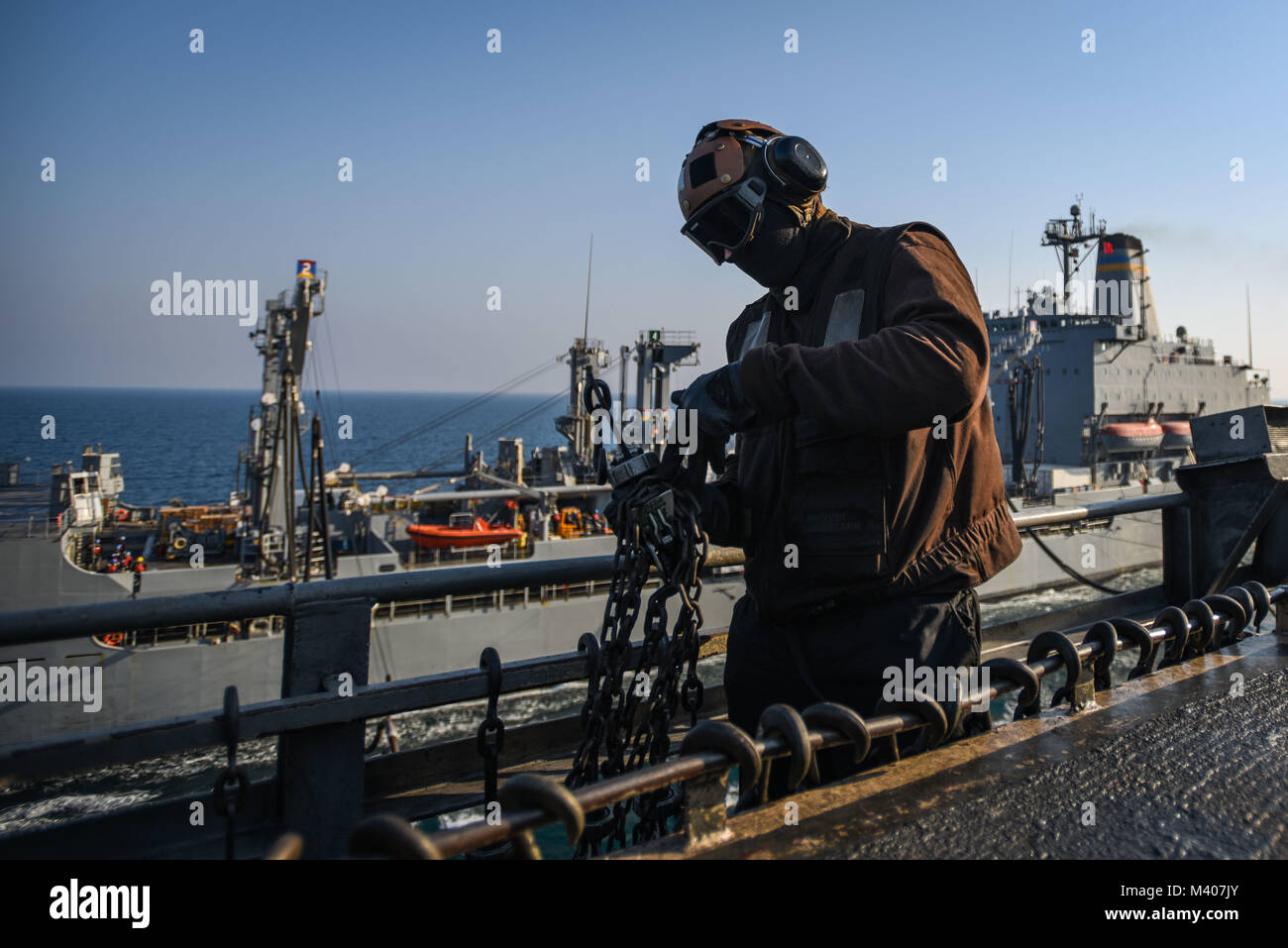 180208-N-VN584-1449 ARABIAN GULF (Feb. 8, 2018) Aviation Ordnanceman Airman Jake Medill, assigned to the Cougars of Electronic Attack Squadron (VAQ) 139, stows chains on the flight deck of the aircraft carrier USS Theodore Roosevelt (CVN 71) during a replenishment-at-sea with the fleet replenishment oiler USNS Guadalupe (T-AO-200). Theodore Roosevelt and its carrier strike group are deployed to the U.S. 5th Fleet area of operations in support of maritime security operations to reassure allies and partners and preserve the freedom of navigation and the free flow of commerce in the region. (U.S. Stock Photo