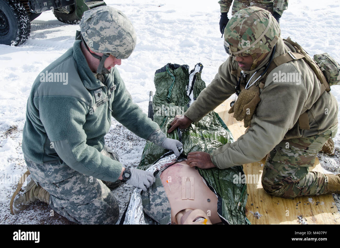 FORT MCCOY, Wis. - U.S. Army Reserve Staff Sgt. Javar Manley (right) and Spc. Jonathan Hessel, medics, Task Force Triad, Operation Cold Steel II, cover an emergency patient simulator with an emergency blanket during a medical evacuation rehearsal at Fort McCoy, Wis., Feb. 8, 2018. Operation Cold Steel is the U.S. Army Reserve’s crew-served weapons qualification and validation exercise to ensure America’s Army Reserve units and Soldiers are trained and ready to deploy on short-notice as part of Ready Force X and bring combat-ready and lethal firepower in support of the Army and our joint partne Stock Photo