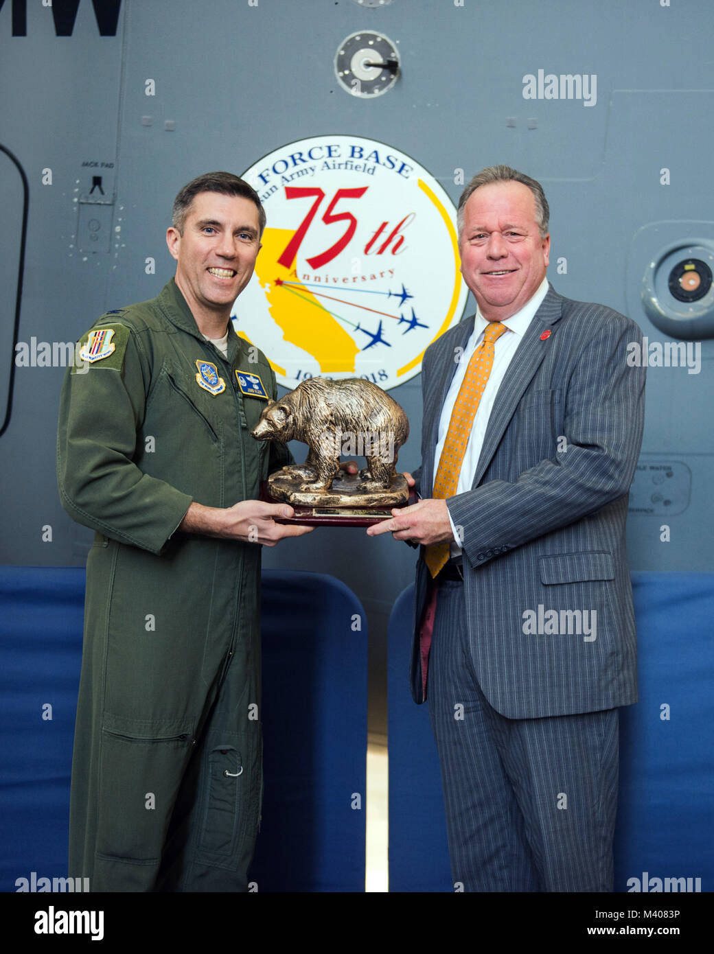 U.S. Air Force Col. John Klein, 60th Air Mobility Wing commander, presents State Senator Bill Dodd (D-Napa), 3rd Senate District, with a Golden Bear during the 75th Anniversary kickoff celebration at Travis Air Force Base, Calif., Feb. 8, 2018. The celebration featured the inaugural unveiling of the 75th Anniversary logo on a C-17 Globemaster III. Travis is celebrating 75 years as a major strategic logistics hub for the Pacific and integral part of global power projection for the total force. (U.S. Air Force photo by Louis Briscese) Stock Photo