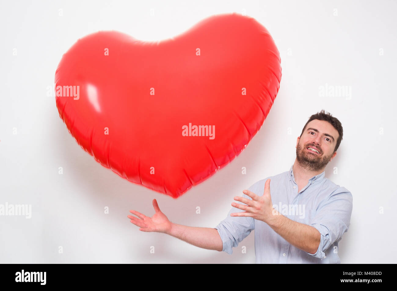 Enamored man hugging a big heart shaped red balloon Stock Photo