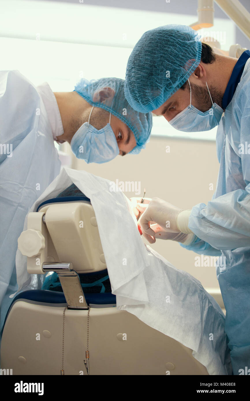 Two surgeons in blue robes make operation in surgery room Stock Photo