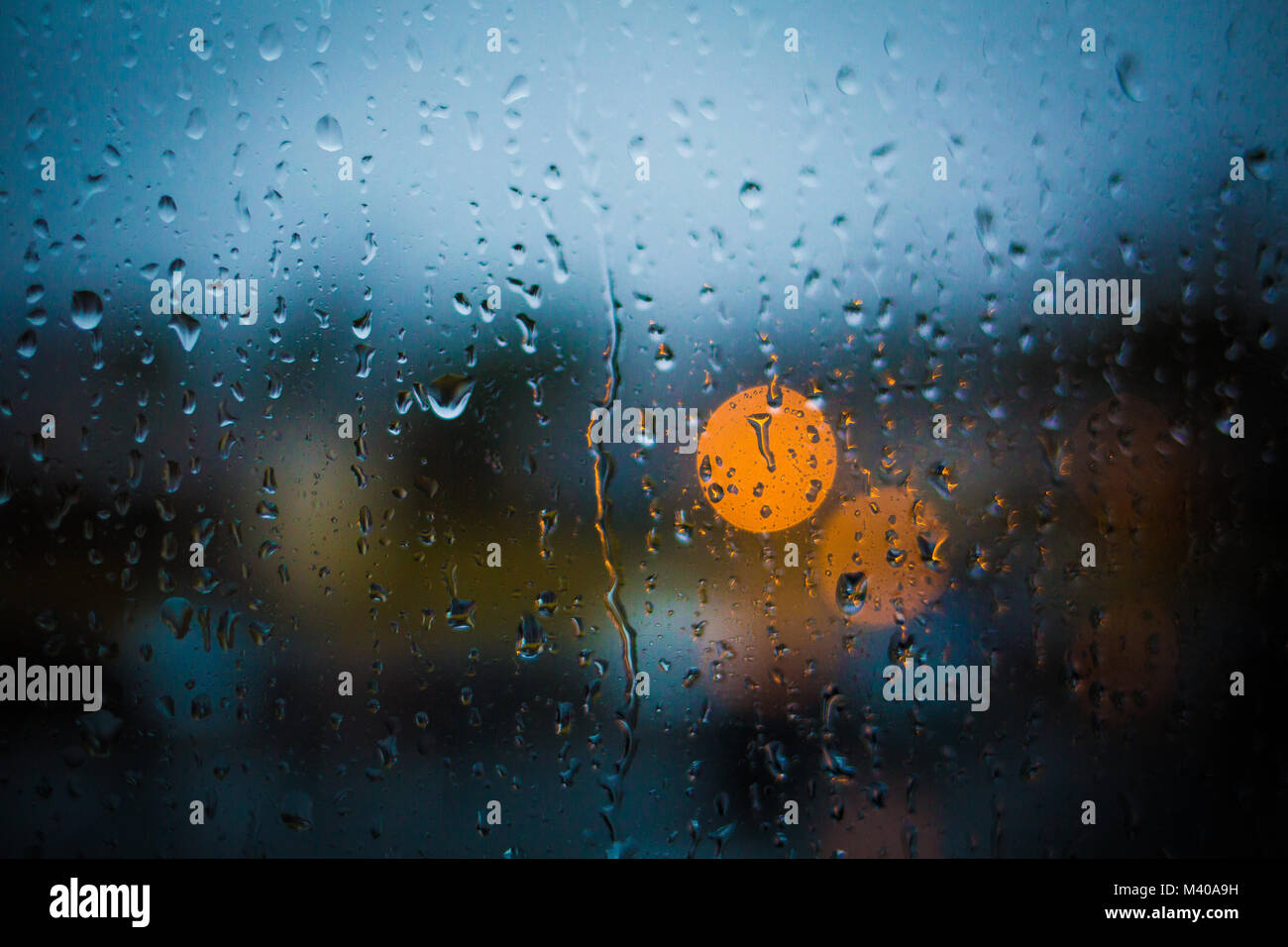 Rain drops on window. Peaceful evening or night at home when raining outside. Water drops on glass. Surface of wet glass. Water splash. City lights bo Stock Photo