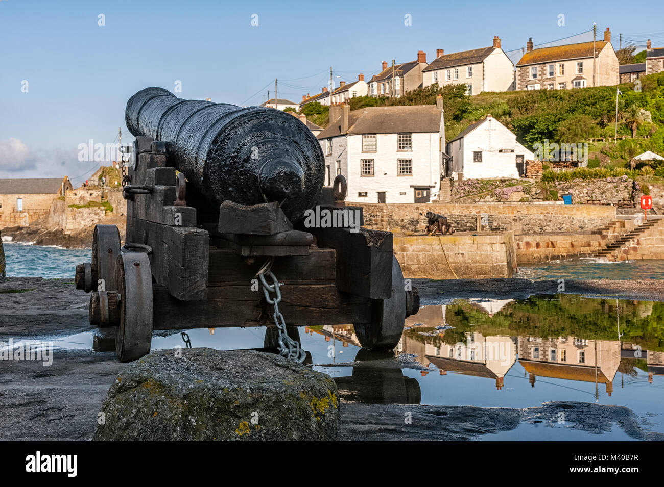 PORTHLEVEN, CORNWALL, UK - JUNE 10, 2009:  Old Naval gun on the Harbour walls with view of the village in the background Stock Photo