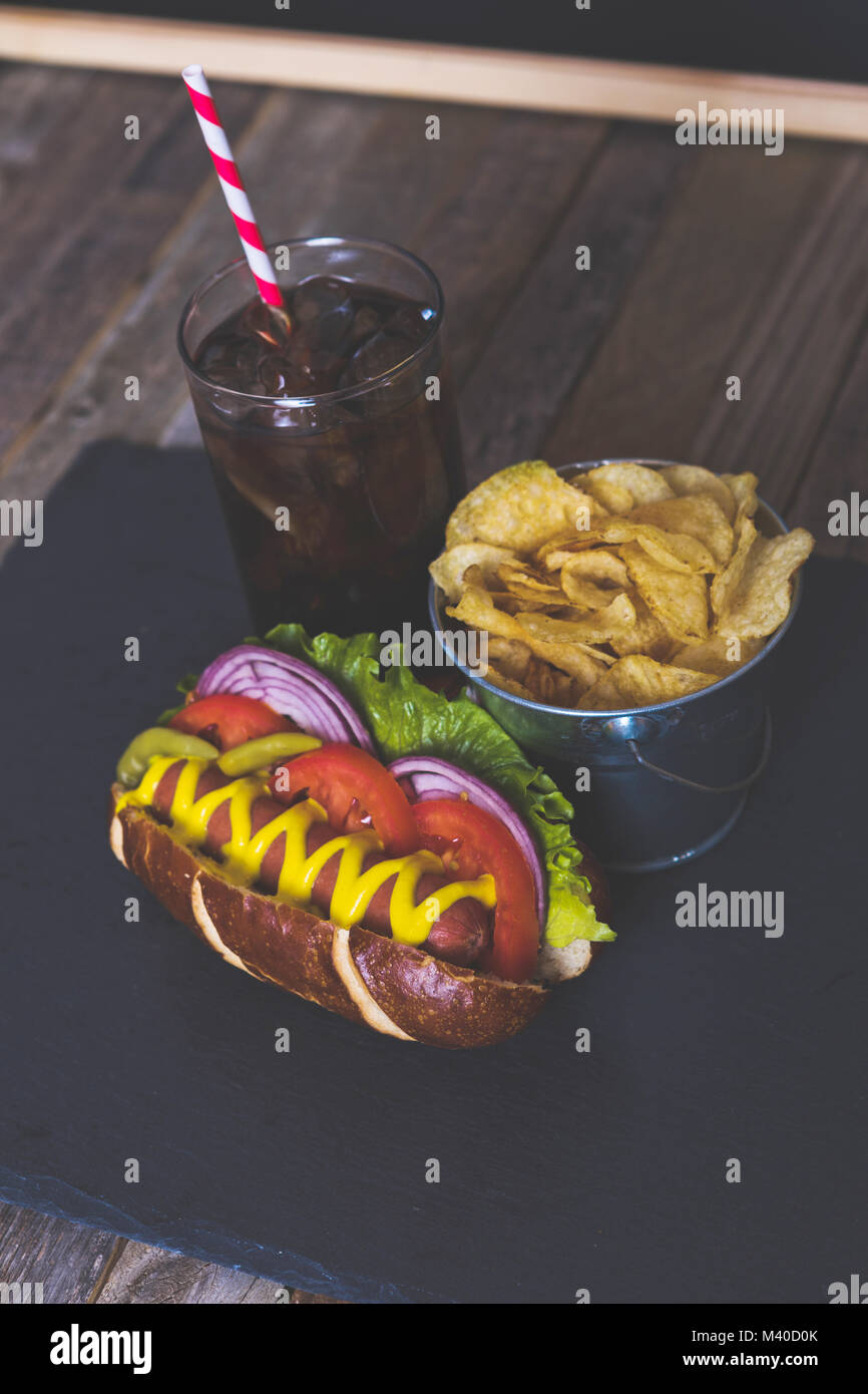 Delicious hot dog with toppings on dark background. Tabletop, side view