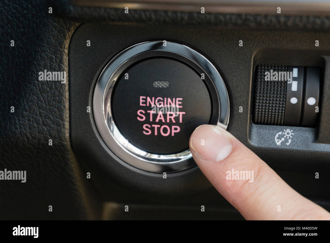 Pushing the engine start stop button of a car Stock Photo