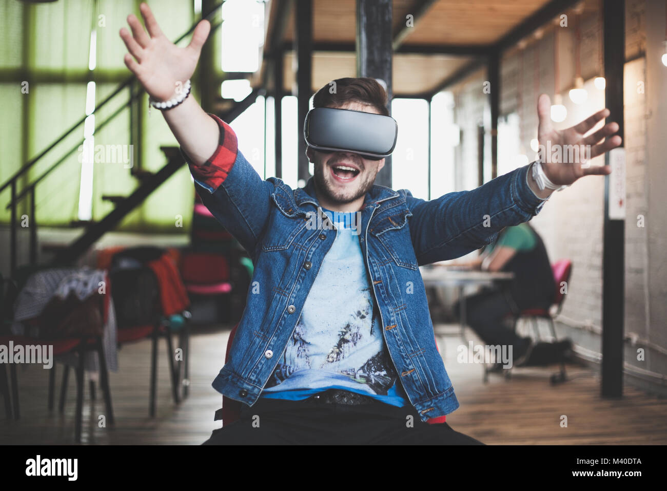 Young man wearing virtual reality glasses in modern interior design ...
