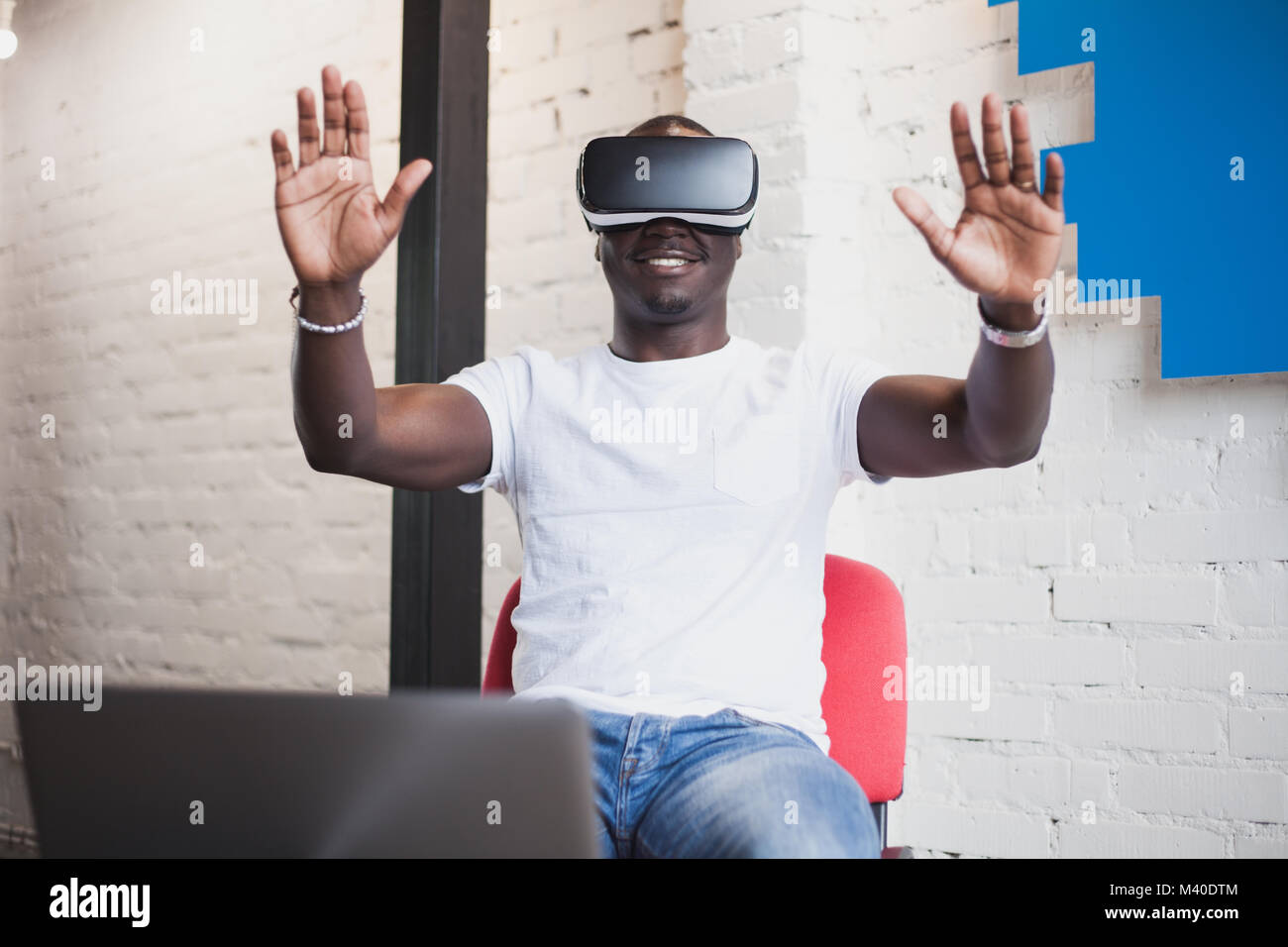 African young man wearing virtual reality glasses in modern interior ...