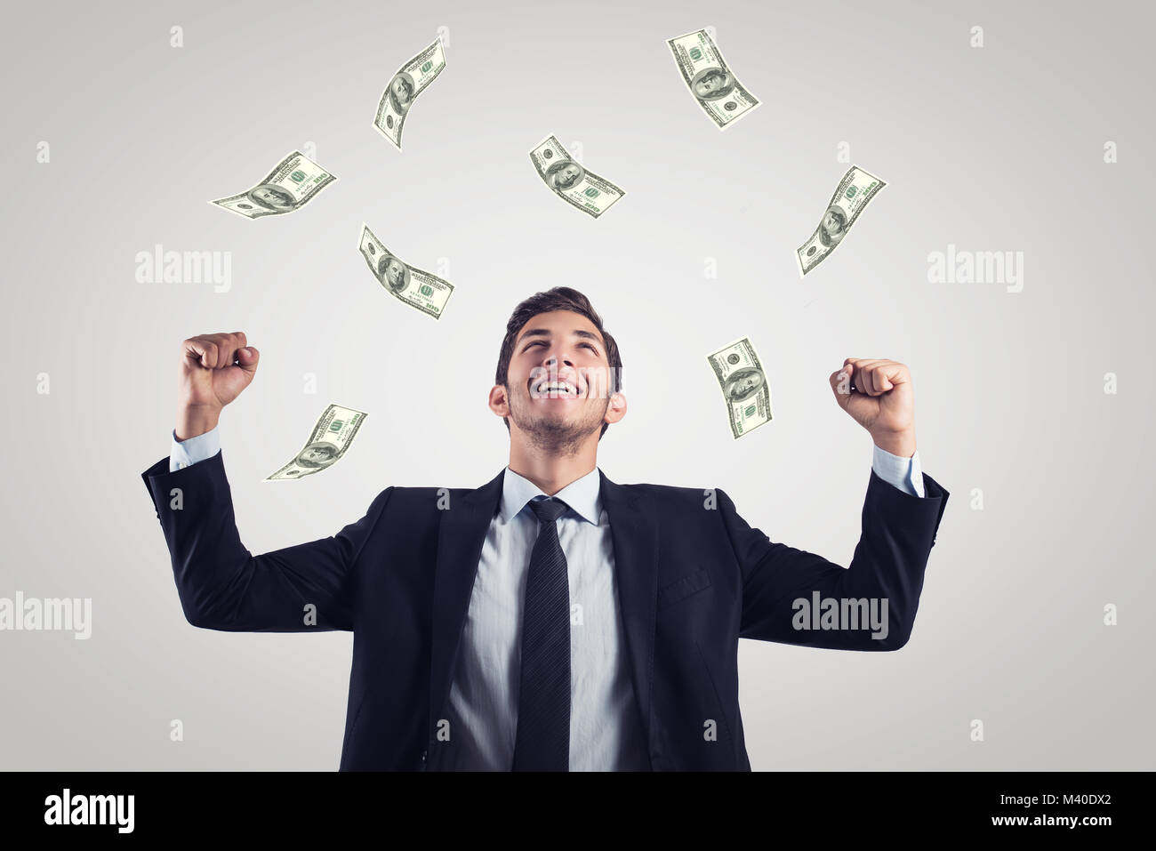 happy excited businessman raising hands up and looking up under money rain. Stock Photo