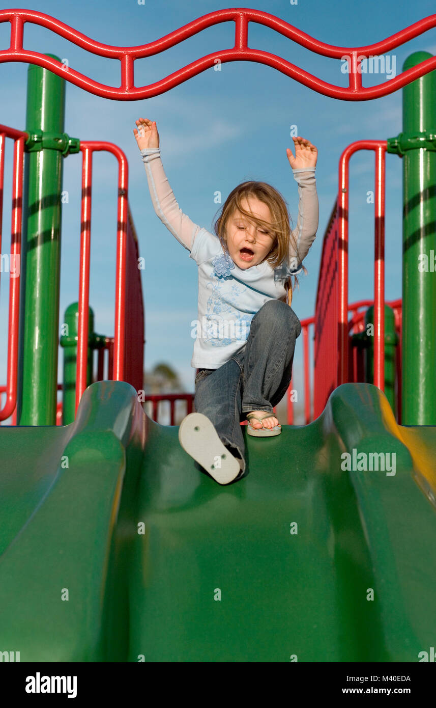 A young girl sliding down a green sliding board Stock Photo Alamy