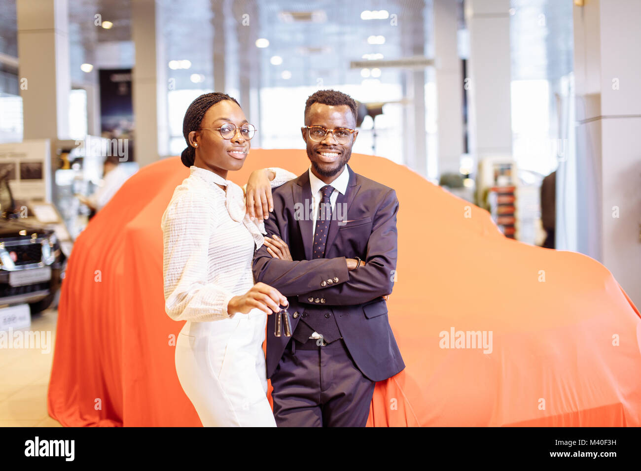 Visiting car dealership. couple holding key of their new car, looking