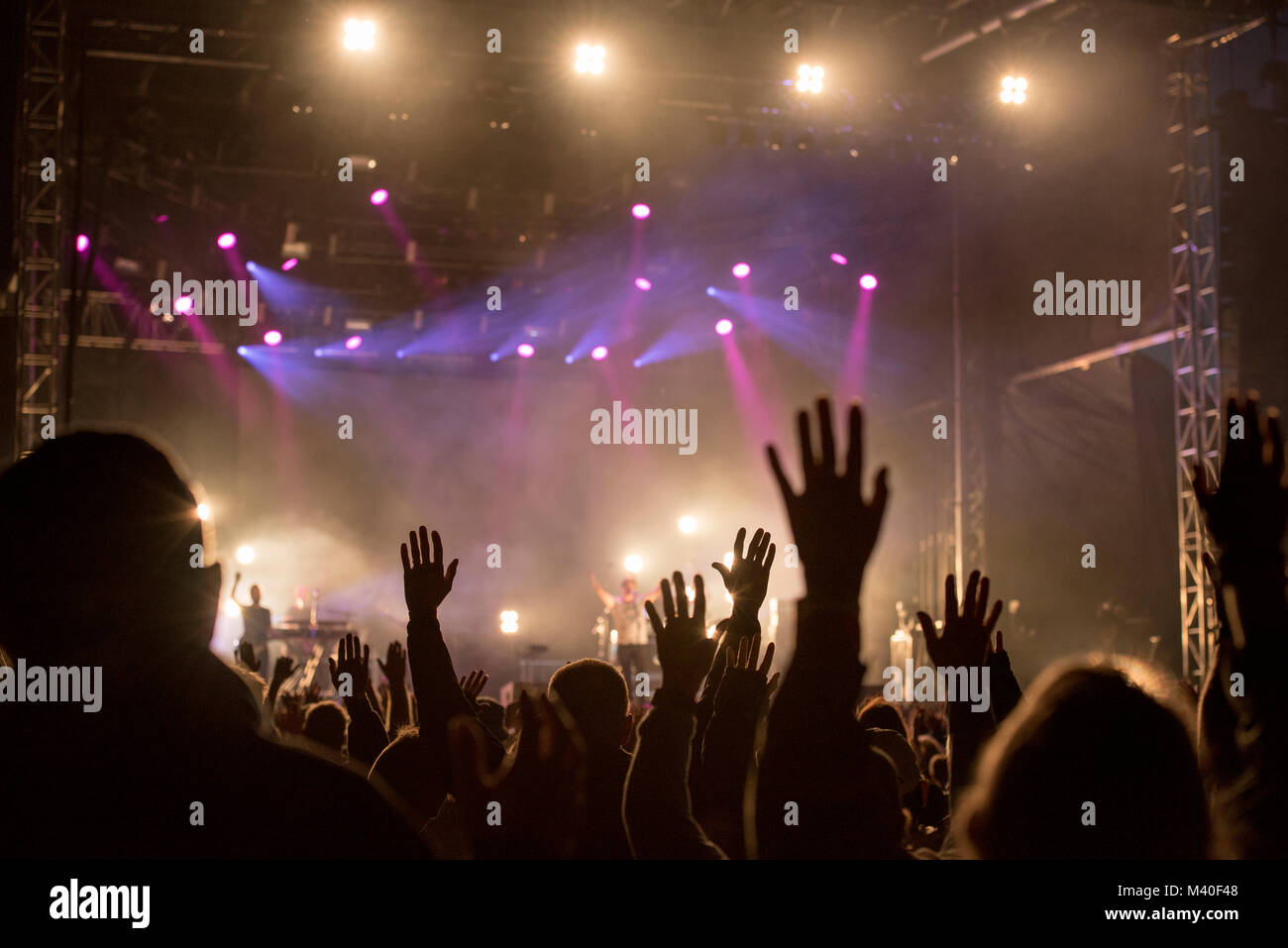 Christians raising their hands in praise and worship at a night music concert Stock Photo