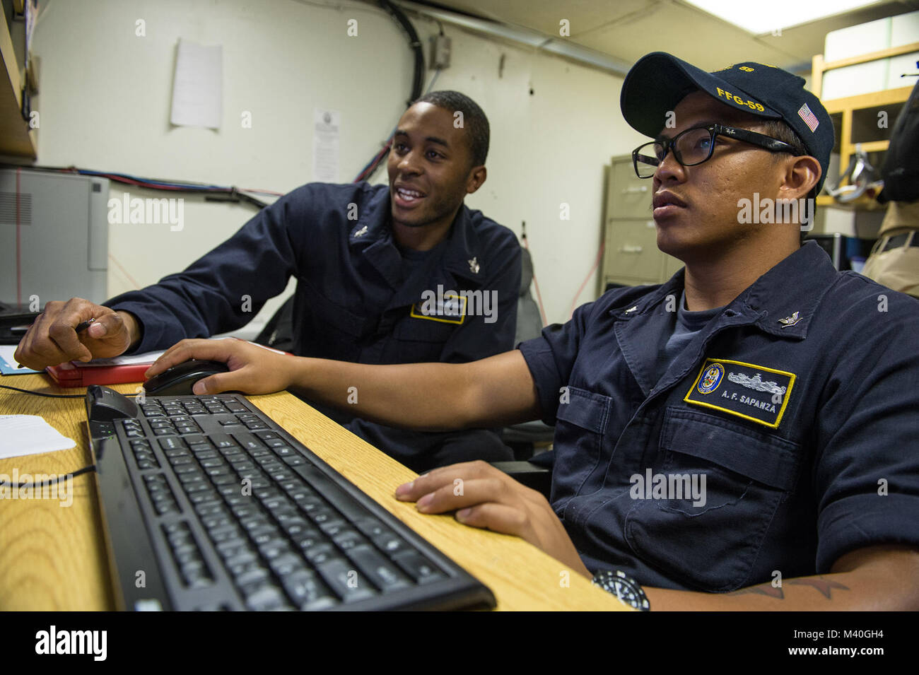 150205-N-IG780-762 CARIBBEAN SEA (Feb. 5, 2015) — Personal Specialist 1st Class George Martin, left, trains Personnel Specialist 3rd Class Anthony Sapanza Jr. on how to use the Personnel Tempo program on board guided-missile frigate USS Kauffman (FFG 59). Kauffman is currently underway in support of Operation Martillo, a joint operation with the U.S. Coast Guard and partner nations within the 4th Fleet area of responsibility. (U.S. Navy photo by Mass Communication Specialist 3rd Class Shane A. Jackson/Released) 150205-N-IG780-762 Stock Photo