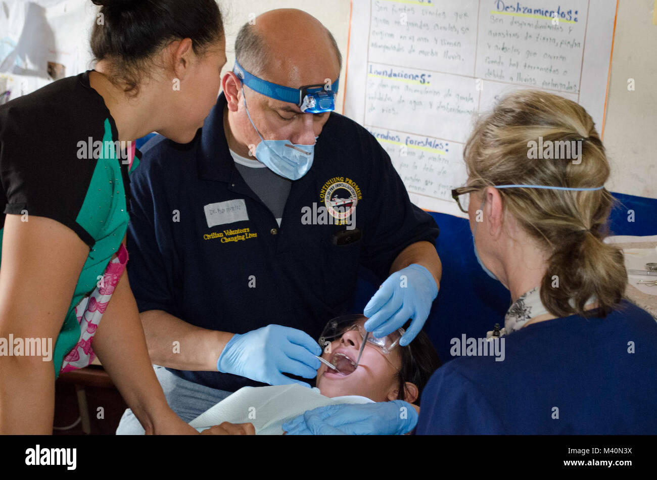 150618-N-KA456-019 SAN JULIAN, El Salvador (June 18, 2015) - A dental assistant with the non-governmental organization (NGO) University of California San Diego Pre-Dental Society (UCSD PDS) and a Salvadoran dentist perform a dental procedure on a patient at a medical site established at Centro Escolar Doctor Eduardo Enrique Barrientos during Continuing Promise 2015 (CP-15). UCSD PDS volunteers are working alongside other NGOs and U.S. and partner nation military members during. Continuing Promise is a U.S. Southern Command-sponsored and U.S. Naval Forces Southern Command/U.S. 4th Fleet-conduct Stock Photo