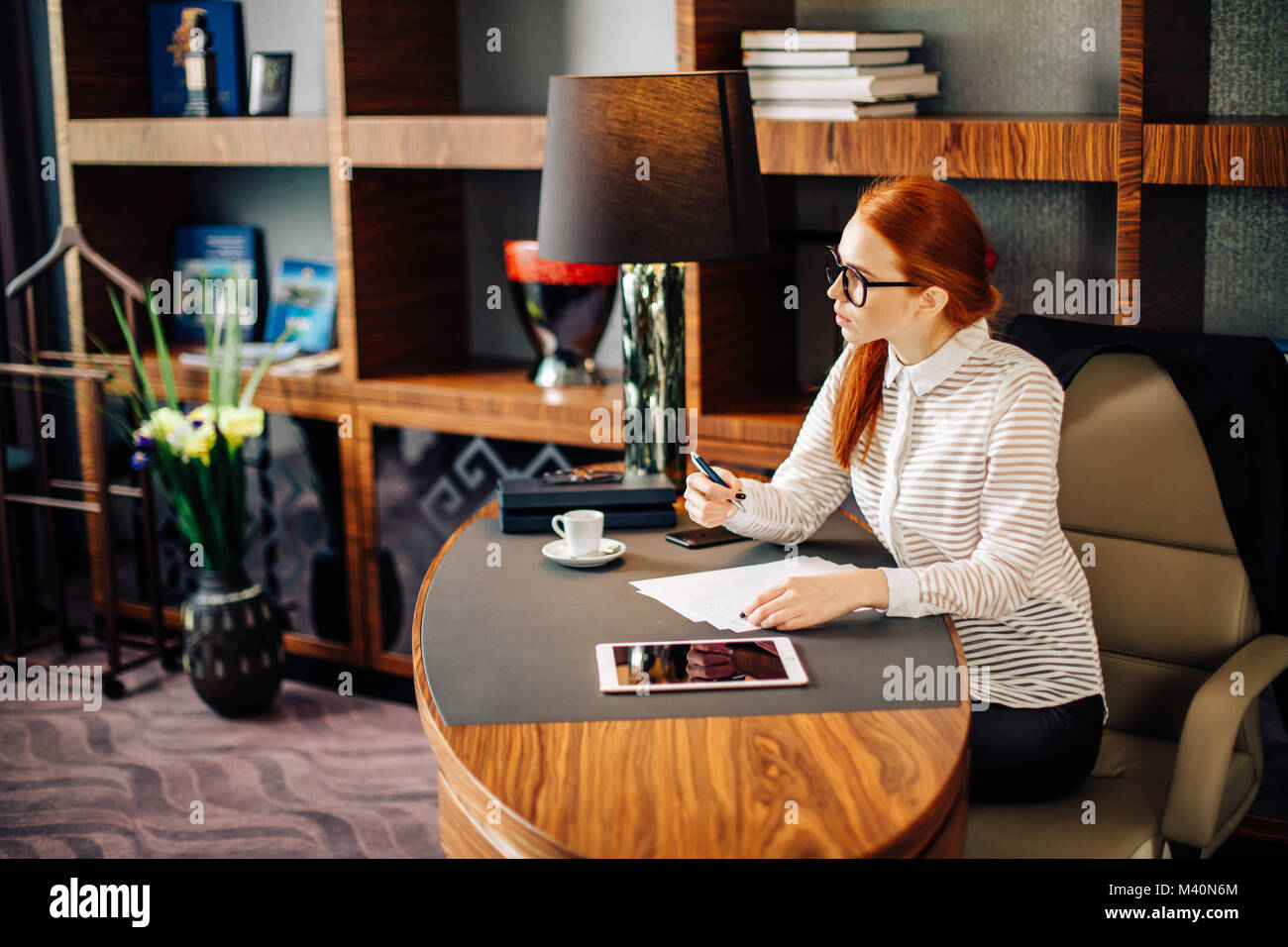 woman writing on paper with digital tablet computer in office room ...
