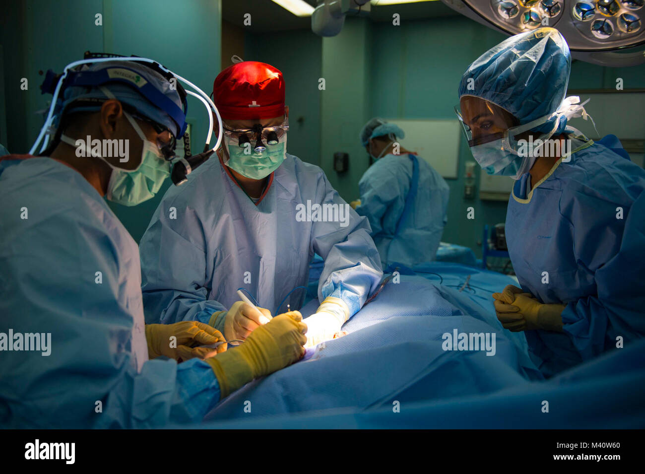 150730-N-XQ474-386 ROSEAU, DOMINICA (July 30, 2015) – Cmdr. Thomas Chung, a native of Los Angeles, Calif., and plastic surgeon assigned to Walter Reed National Military Medical Center Bethesda, Md., and medical students from Ross University School of Medicine perform surgery on a patient in an operating room aboard the Military Sealift Command hospital ship USNS Comfort (T-AH 20) during Continuing Promise 2015.  Continuing Promise is a U.S. Southern Command-sponsored and U.S. Naval Forces Southern Command/U.S. 4th Fleet-conducted deployment to conduct civil-military operations including humani Stock Photo