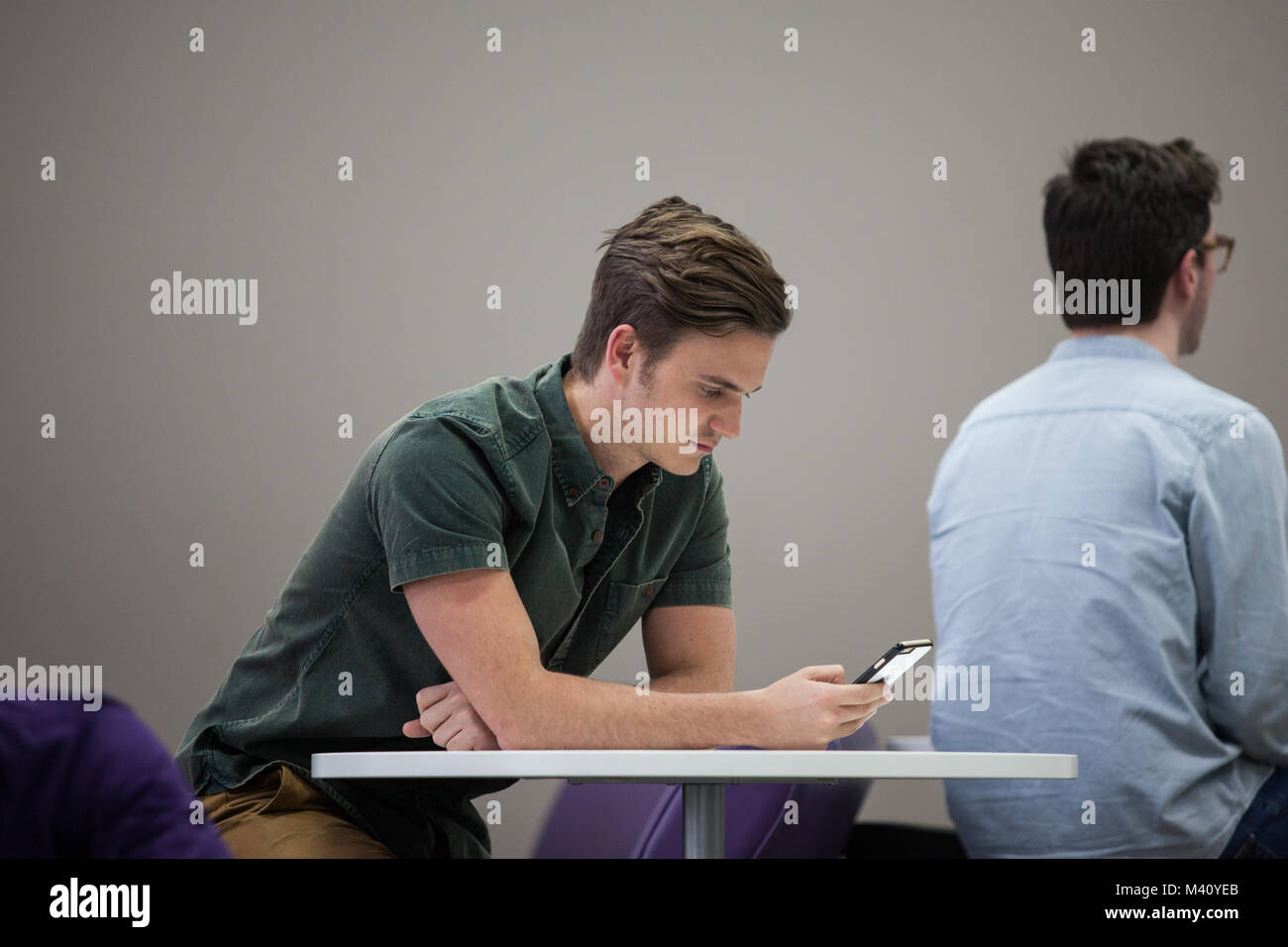 Man using smartphone in waiting area Stock Photo