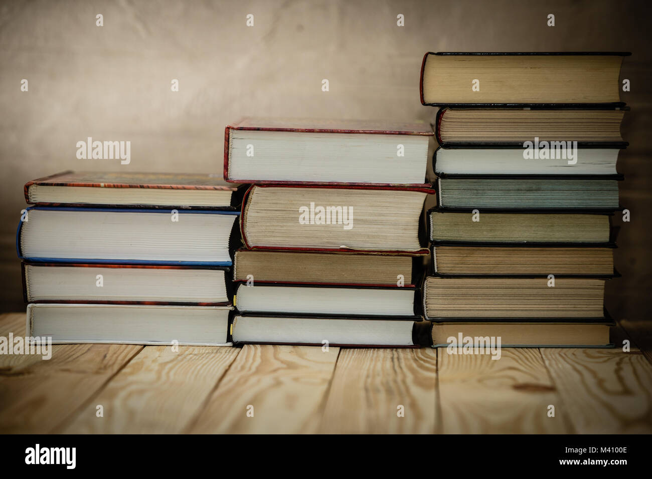 Textbooks and books on a wooden table. Book stack in the library room and blurred bookshelf for business and education background. Stock Photo