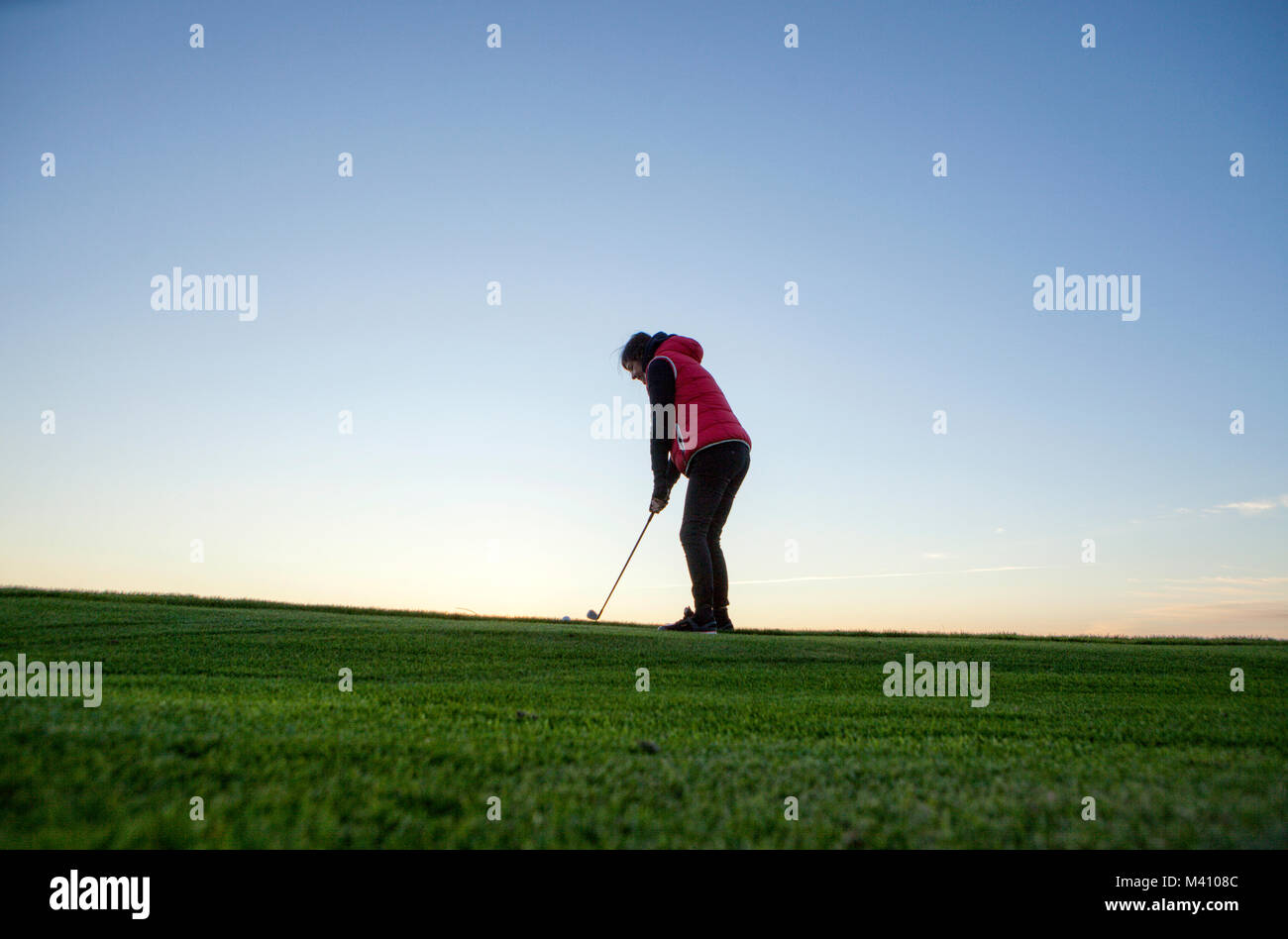 A Woman golfer playing golf with her son in a jogging stroller during a