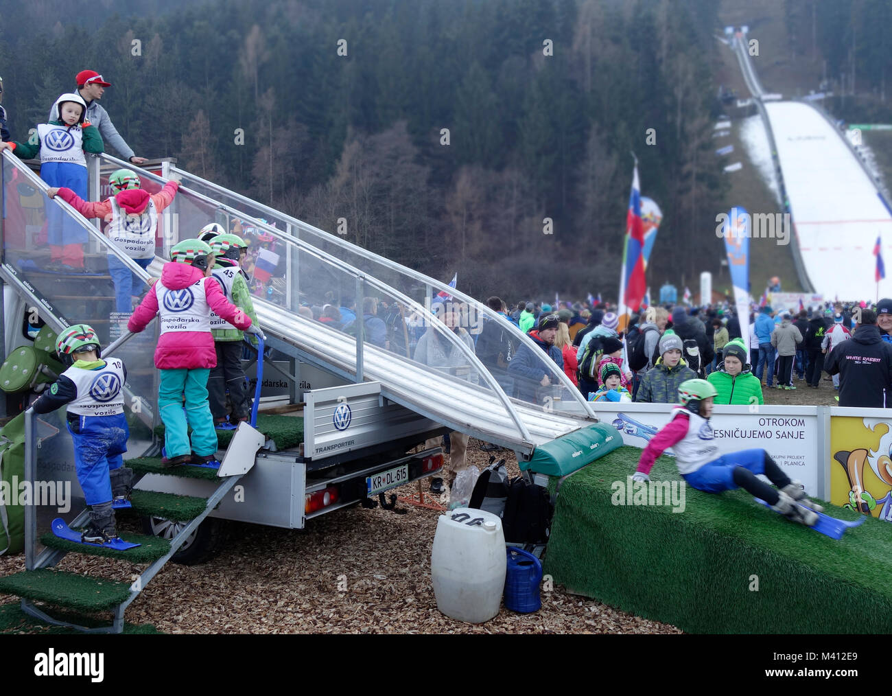Young kids play on the 'baby ski jumping hill' for children. Ljubno ob Savinji, Slovenia. Stock Photo