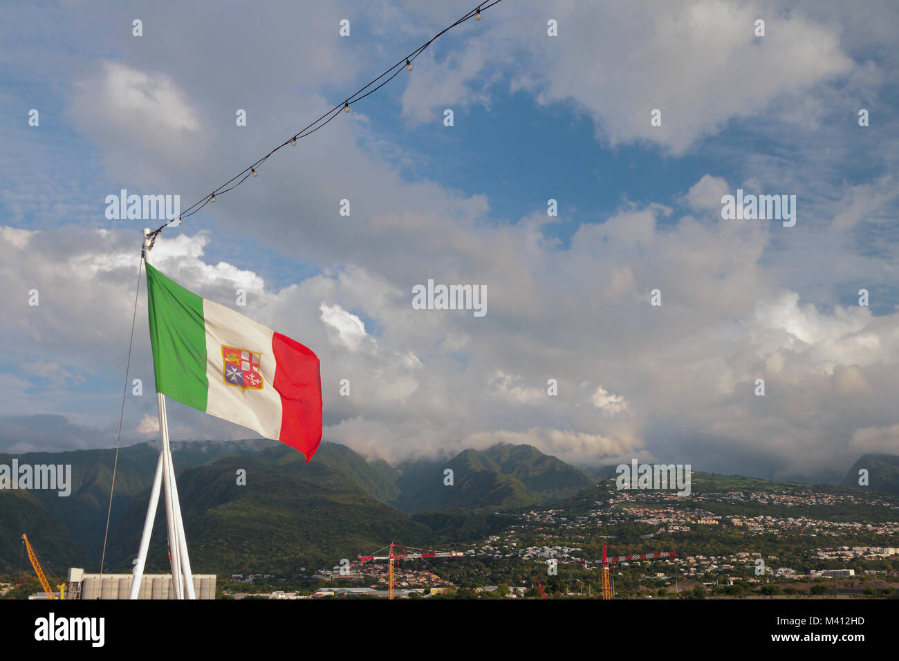 Italian flag with Maltese symbolics against background of hilly terrain. Boeuf-mort, Reunion Stock Photo