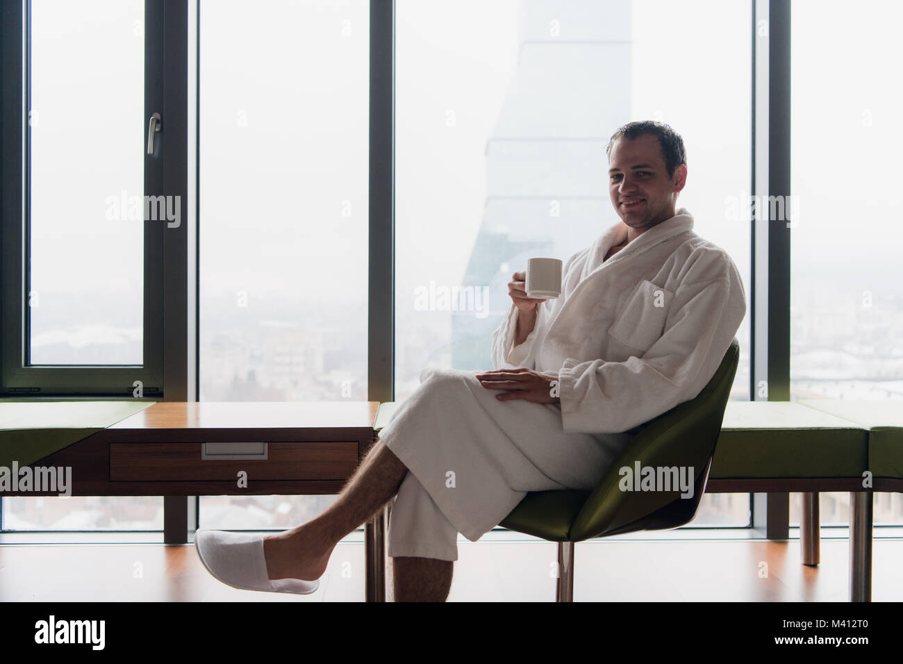 man in bathrobe drinks coffee in luxury hotel in the morning. Stock Photo