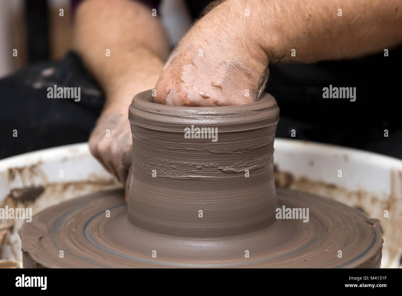Close up detail view at an artist makes clay pottery on a spin wheel