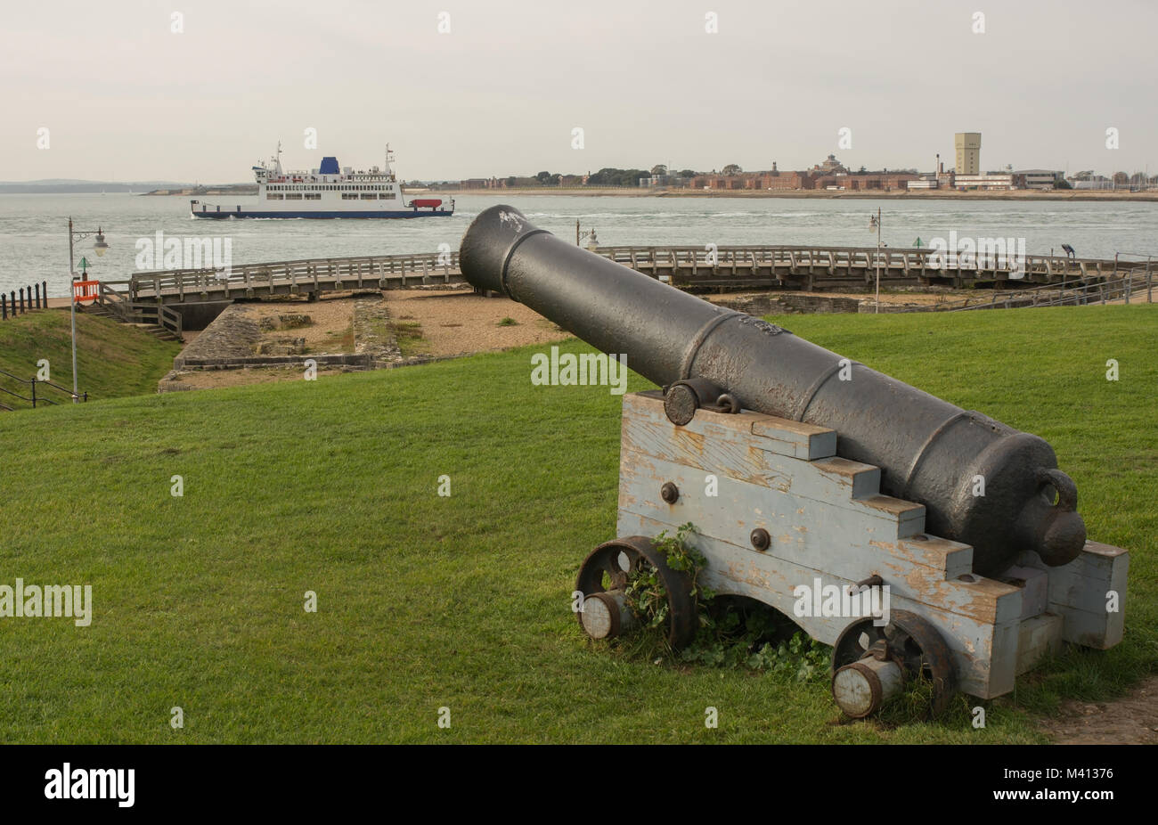 Old Naval Cannon at Entrance to Portsmouth Harbour in Hampshire, England. With Isle of Wight ferry boat on Solent water Stock Photo