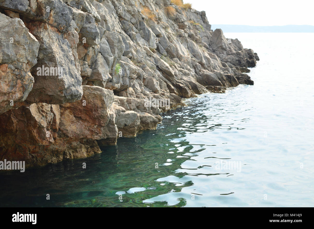 Beach rocks with green sea water in summer Stock Photo - Alamy