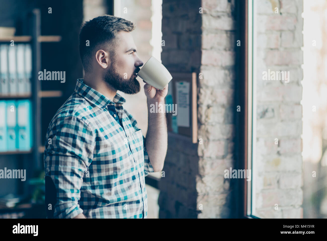 Portrait of confident experienced calm peaceful concentrated bearded handsome guy having a recreating after hard working day, he is standing near wind Stock Photo