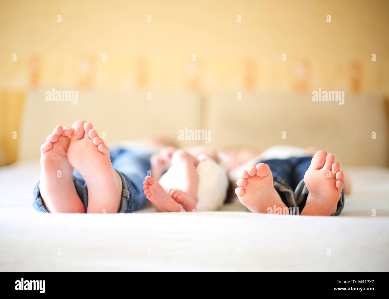 Sweet family in bed. Three sisters, close up on feet. Holiday and happiness concept Stock Photo