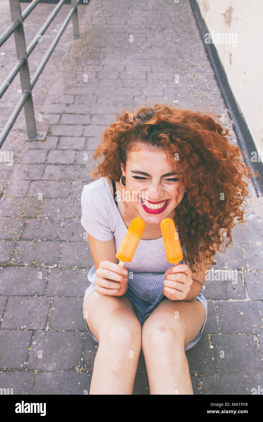 Redhead young woman eating ice creams in summer Stock Photo